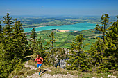 Frau beim Wandern steigt zum Tegelberg auf, Forggensee im Hintergrund, Tegelberg, Ammergauer Alpen, Schwaben, Bayern, Deutschland