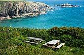Picknicktische aus Holz auf einer Klippe an der Küste von Pembrokeshire, Wales, Großbritannien