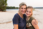 Frau und junges Mädchen (Mutter und Tochter) am Ufer eines breiten Flusses
