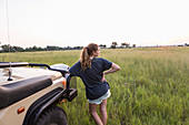 Dreizehnjähriges Mädchen stützt sich auf Safari-Jeep, Botswana