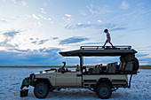 6 year old boy and older sister standing on top of safari vehicle, Nxai Pan, Botswana