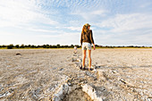 13 year old girl leaping into elephant footprints, Nxai Pan, Botswana