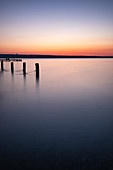 Blick auf den Ammersee bei Sonnenuntergang, Links Holzpfeiler vom Anlegesteg, Bayern, Deutschland, Europa