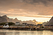 Sonnenuntergang über dem Fischerdorf und den Bergen im Hintergrund, Sakrisoya, Provinz Nordland, Lofoten, Nordnorwegen, Europa