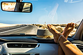 Weibliche Füße auf dem Armaturenbrett im fahrenden Auto