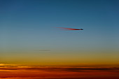 Airplane with contrails just before sunrise
