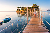 Junge Frau geht auf einer Hängebrücke aus Holz über dem Meer, die zur Insel Cameo führt, Agios Sostis, Zakynthos, Ionische Inseln, Griechenland, Europa
