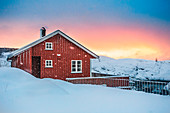 Typisches rotes Haus spiegelt sich im Meer, Reine, Lofoten, Nordnorwegen