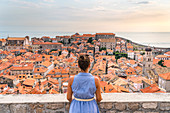 Woman staring at the red roofs of the town from the old walls. Dubrovnik, Dubrovnik - Neretva county, Croatia.