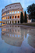 View of the Colosseum reflecting on a puddle during a winter evening. Rome, Lazio, Italy. 