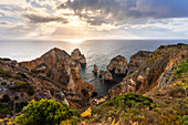 Cloudy sunrise at the yellow and red cliffs of Ponta da Piedade. Lagos, Algarve, Portugal, Europe.