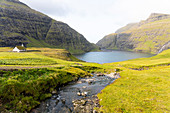 View of the lagoon and church with grassy roof in one of the most beautiful places in the world, Saksun, Streymoy Island in the Faroe Islands.