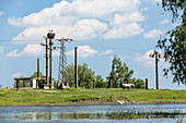 White stork (Ciconia ciconia) on power pole ruin, and a horse on a canal bank in the Danube Delta in April, Tulcea, Romania.