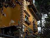 Quartiere Coppede, Rom, Italien: Detail eines gelben Gebäudes mit zwei kleinen schmiedeeisernen Balkonen und Wanddekorationen im Jugendstil