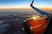 Blick aus dem Flugzeugfenster bei Sonnenaufgang, Flugzeugflügel