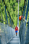 Woman walks over the Kuonen suspension bridge, longest suspension bridge in the Alps, Kuonen suspension bridge, Europaweg, Randa, Valais Alps, Valais, Switzerland