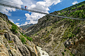 Frau beim Wandern geht über Aletsch-Hängebrücke, UNESCO Weltnaturerbe Jungfrau-Aletsch, Berner Alpen, Schweiz