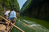 Chinesische Männer rudern ein traditionelles Sampan-Boot in der Nähe von Badong am Shennong-Strom, einem Nebenfluss des Jangtse an der Wu-Schlucht (Drei Schluchten) in China.