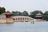 Der Kunming-See mit der Insel Nanhu und die 17-Bogen-Brücke im Sommerpalast, dem kaiserlichen Garten der Qing-Dynastie in Peking, China.