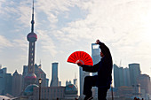 Üben von Tai Chi mit Fächer und Pudong-Skyline, früher Morgen, Shanghai, China