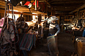 Cowgirl nimmt Sattel und Decke aus dem Lagerraum, Ranch, Britisch-Kolumbien, Kanada