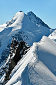 Mountaineers climbing Breithorn Centrale from Breithorn Occidentale, Lyskamm on background, Aosta Valley, Italy, Europe