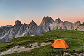 Mount Campedelle, Misurina, Auronzo di Cadore, province of Belluno, Veneto, Italy, Europe. A mountaineer admires the sunrise in the Cadini di Misurina mountains
