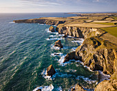 Aerial View of Bedruthan Steps in Cornwall, small secluded beach with steep cliffs and rock stacks offshore. High tide.