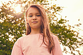 Porträt des lächelnden Mädchens mit dem langen brünetten Haar, das draußen steht und Kamera betrachtet.