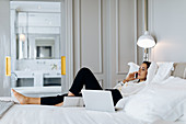 Businesswoman using smartphone and laptop in suite