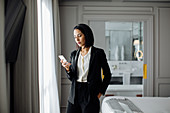 Businesswoman using smartphone in suite