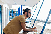 Mann entspannt sich unter Bootsverdeck am Meer, Livorno, Italien