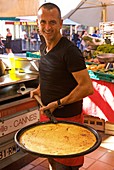 France, Alpes Maritimes, Cannes, Seller of socca, a cake with chickpea flour, on Forville market at the foot of the hill of the Suquet district