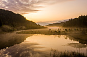 Himmel gemalt orange im Morgengrauen mit nebligem Land des Naturschutzgebiets Pian di Gembro, Luftbild, Aprica, Valtellina, Lombardei, Italien, Europa