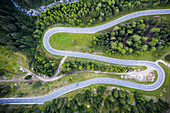 Haarnadelkurve der S-förmigen Straße am Maloja-Pass von oben durch Drohne, Val Bregaglia, Engadin, Kanton Graubunden, Schweiz, Europa
