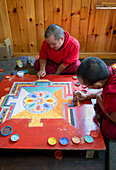 Buddhist monks making a diorama (mandala) with coloured sand, which once made is wiped off to demonstrate transience and impermanence, Bhutan, Asia