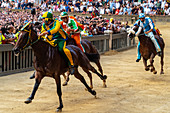 Jockeys in farbenfrohen Outfits, die ihre jeweiligen Nachbarschaften repräsentieren (contrade), wetteifern um die Führung im Palio, Siena, Toskana, Italien, Europa