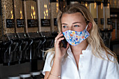Portrait of young blond woman wearing face mask, standing in waste free wholefood store.