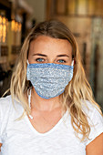 Woman wearing face mask shopping in waste-free local store, sustainability.