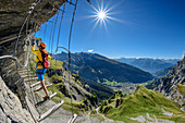 Frau begeht Erlebnisklettersteig Gemmi, Leukerbad und Walliser Alpen im Hintergrund, Gemmi, Berner Alpen, Wallis, Schweiz