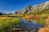 Mann und Frau beim Wandern steigen durchs Baltschiedertal auf, Bergsee im Vordergrund, Wiwannihorn im Hintergrund, Baltschiedertal, Berner Alpen, Wallis, Schweiz
