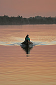 Gambia; Central River Region; Abendrot am Gambia-Fluss bei Kuntaur; zwei Männer in einem Boot
