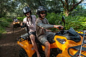 People on an excursion with a quad off-road vehicle on a dirt road through lush mountain vegetation, Bora Bora, Leeward Islands, French Polynesia, South Pacific