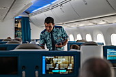 Flugbegleiter reicht Speisekarte an Passagier in der Poerava Business Class an Bord von Air Tahiti Nui Boeing 787 Dreamliner Flugzeug auf dem Flug vom Pariser Flughafen Charles de Gaulle (CDG) in Frankreich zum internationalen Flughafen Los Angeles (LAX) in den USA fliegt