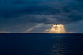 Sonnenstrahlen brechen durch Gewitterwolken nahe Fatu Hiva, Marquesas-Inseln, Französisch-Polynesien, Südpazifik