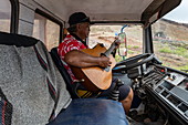Bus driver plays guitar while waiting for group passengers, Tekoapa, Ua Huka, Marquesas Islands, French Polynesia, South Pacific