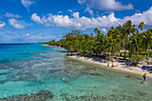 Luftaufnahme von Menschen die sich am von Kokospalmen gesäumten Strand entspannen, Insel Avatoru, Rangiroa-Atoll, Tuamotu-Inseln, Französisch-Polynesien, Südpazifik