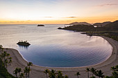 Luftaufnahme von Strand und halbmondförmiger Bucht im Six Senses Fiji Resort bei Sonnenuntergang, Malolo Island, Mamanuca Group, Fidschi-Inseln, Südpazifik