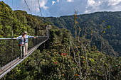 Couple admires view from suspension bridge of Canopy Walkway, Nyungwe Forest National Park, Western Province, Rwanda, Africa