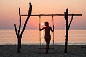 Silhouette von junger Frau auf Schaukel am Ong Lang Beach bei Sonnenuntergang, Ong Lang, Insel Phu Quoc, Kien Giang, Vietnam, Asien